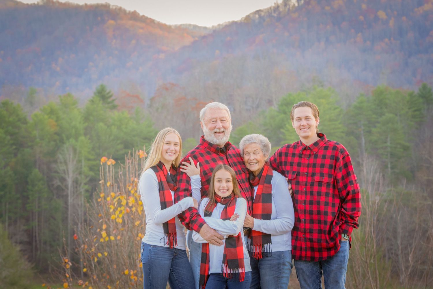 A family of five stands together outdoors with mountains and autumn trees in the background in Townsend Tn.