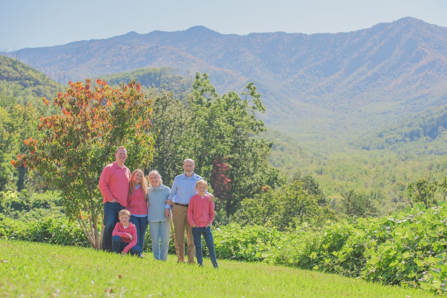 A family reunion enjoy a scenic mountain overlook surrounded by lush greenery and blooming flowers on a sunny day in Gatlinburg TN.