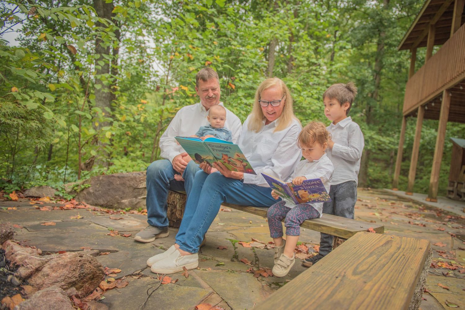 Grandparents and grandkids together on wooden decking in a wooded area while reading books together outdoors in Pigeon Forge Tn.