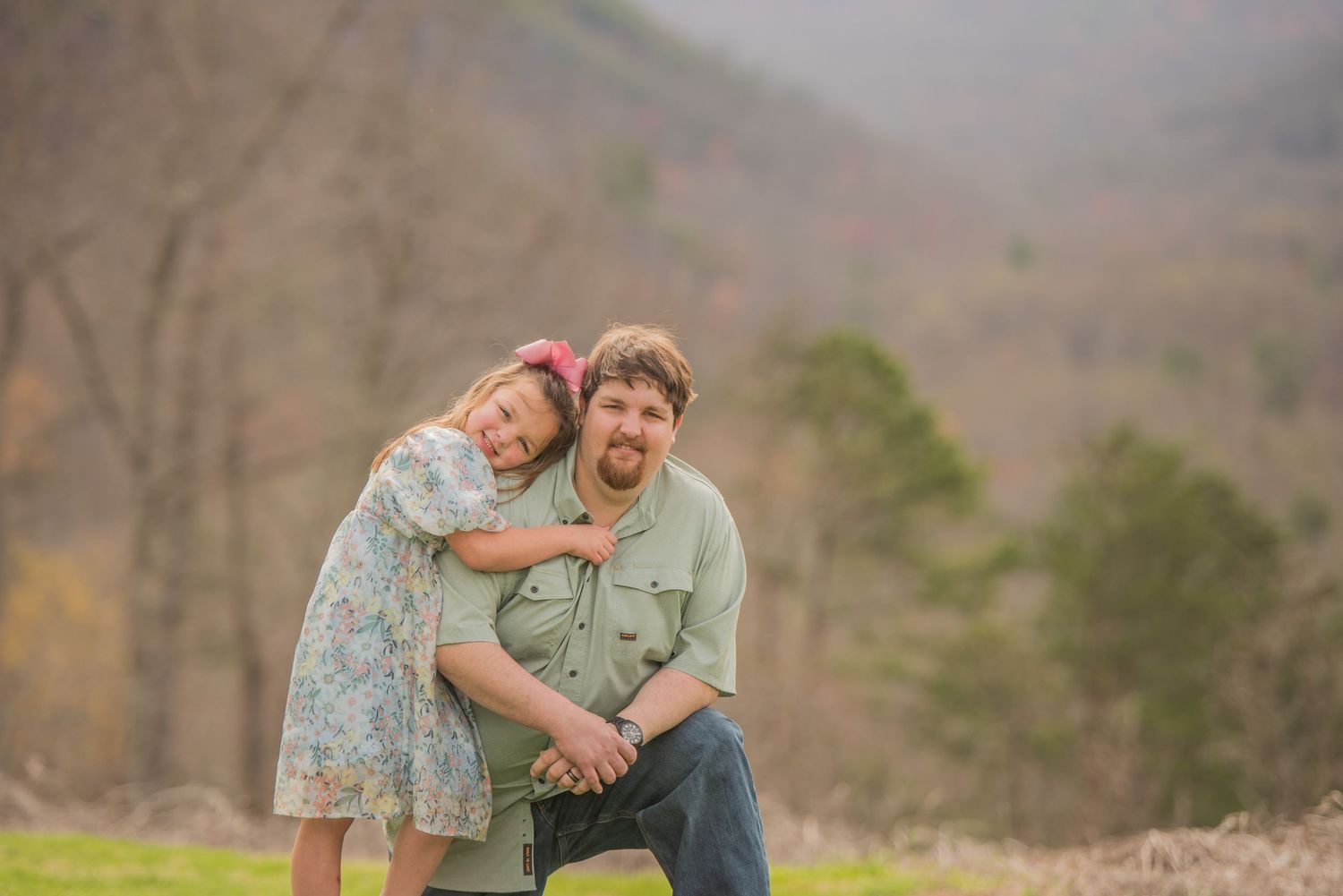 Pigeon Forge Photographers portrait of a parent and child share a tender moment outdoors against a mountain backdrop in springtime.