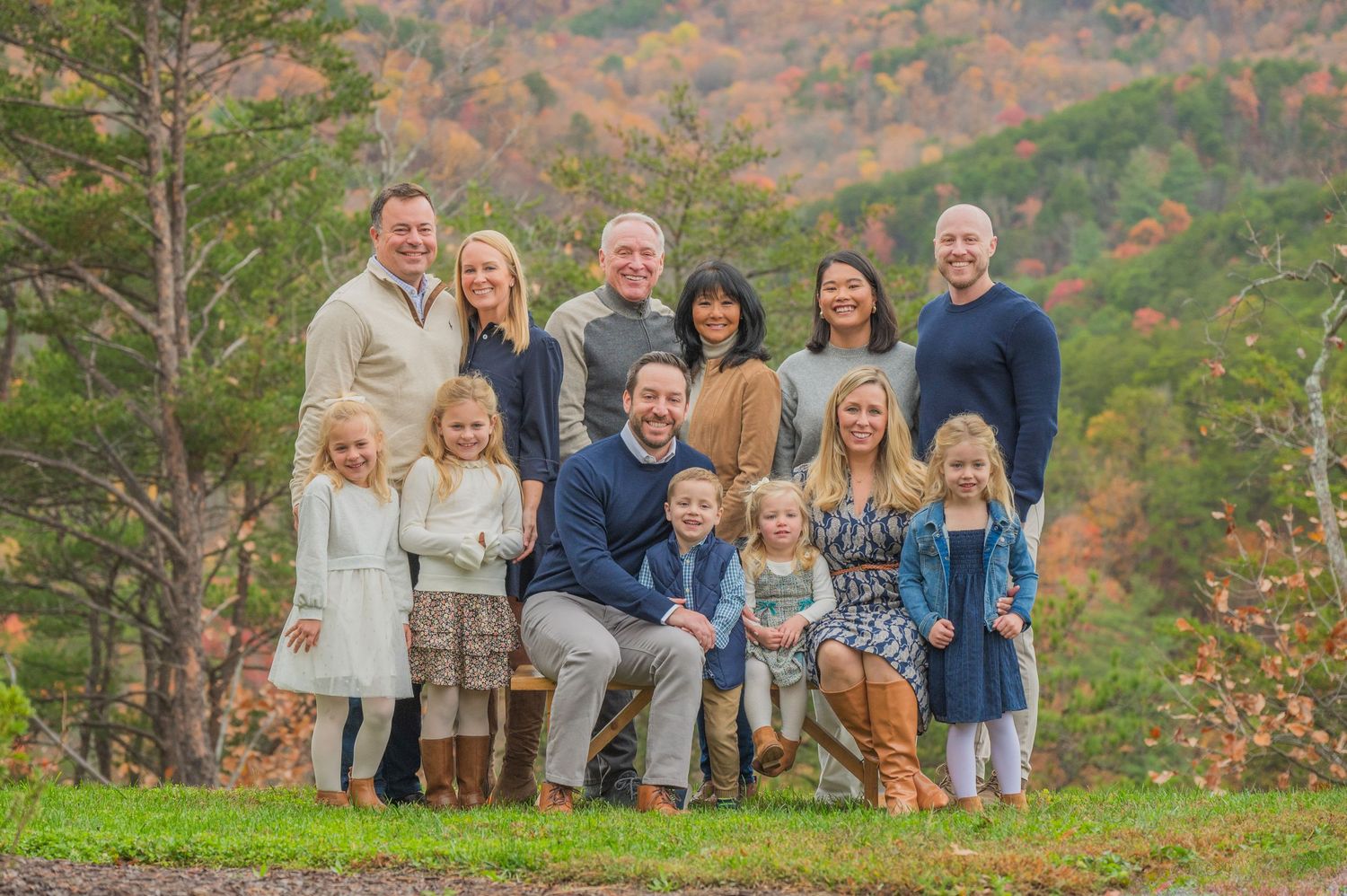 A group of people gathered outdoors for a family portrait against an autumn mountain backdrop by Gatlinburg TN Photographer.
