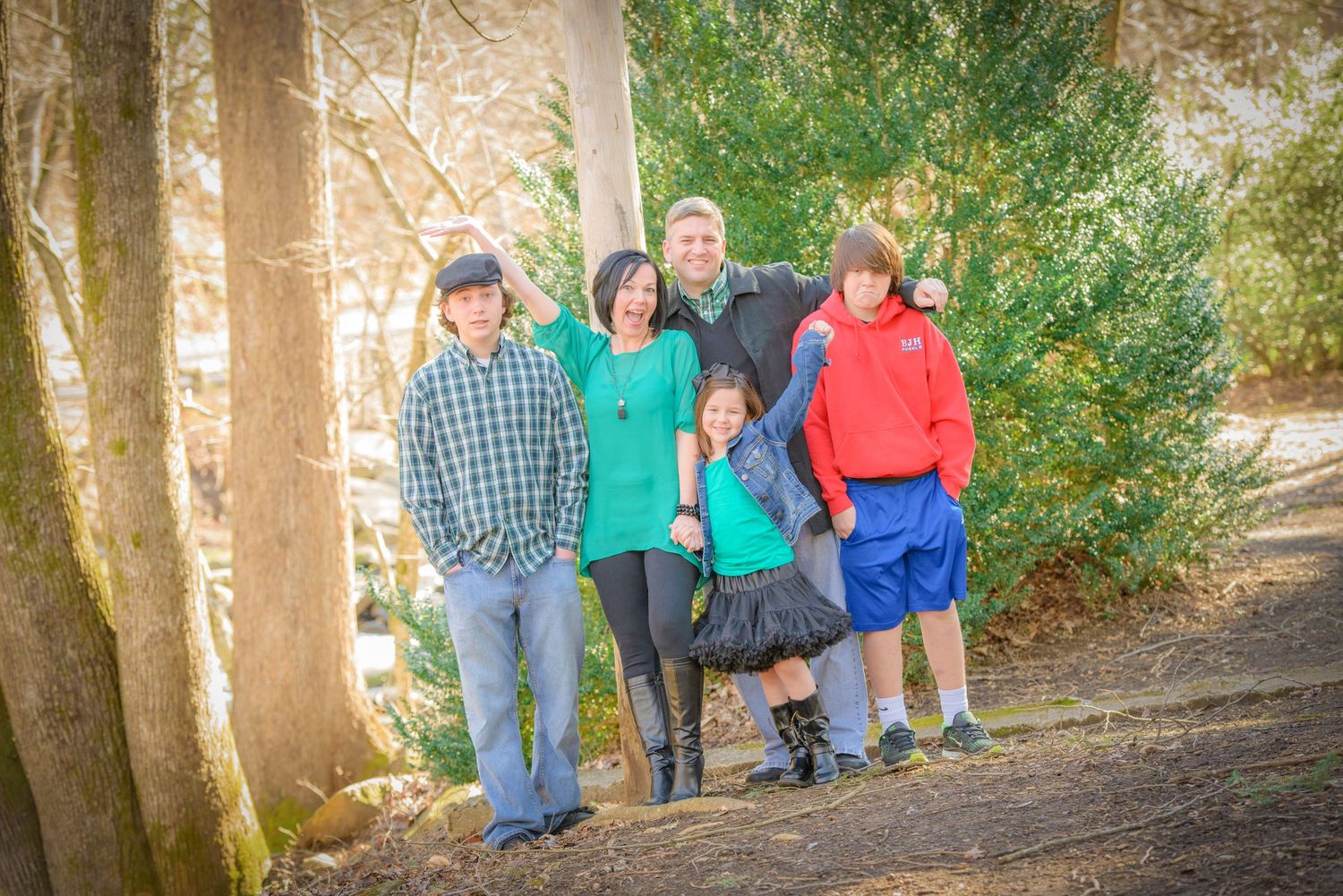 Gatlinburg Photographer portrait of a small group poses together on a wooded path with tall trees and natural lighting on an autumn day.