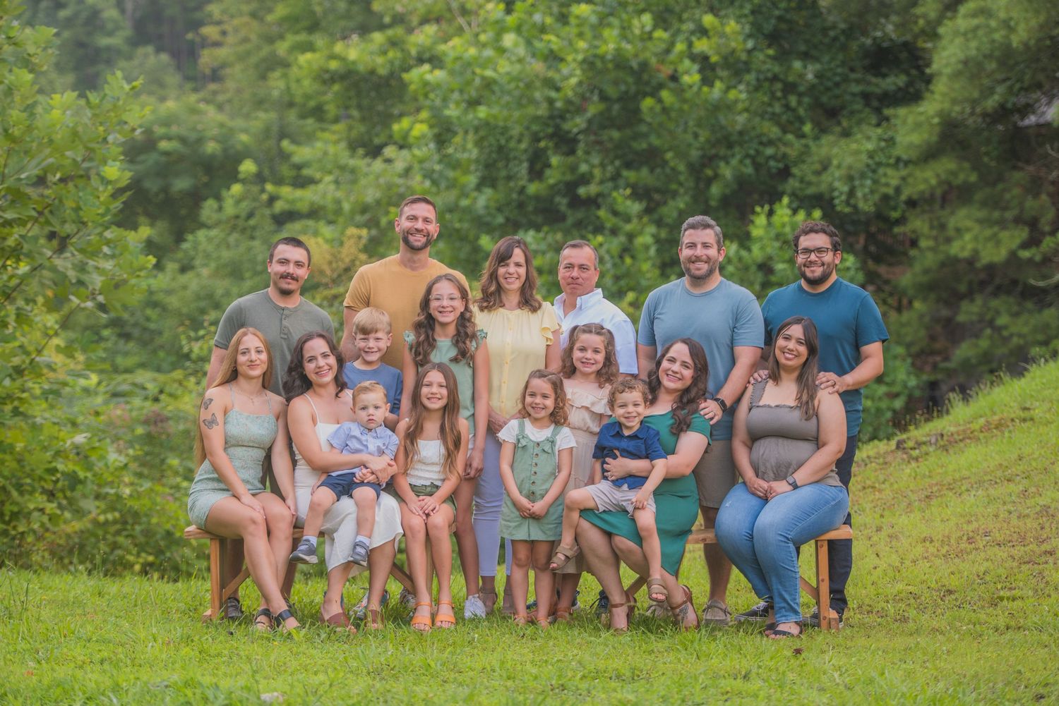 Large group portrait outdoors on a grassy hill with green trees in the background on a summer day by Gatlinburg Photographers TN.