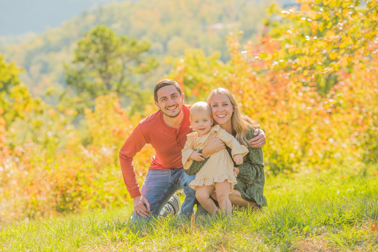 A family sits together on an autumn hillside surrounded by colorful fall foliage at their rental in Sevierville TN.