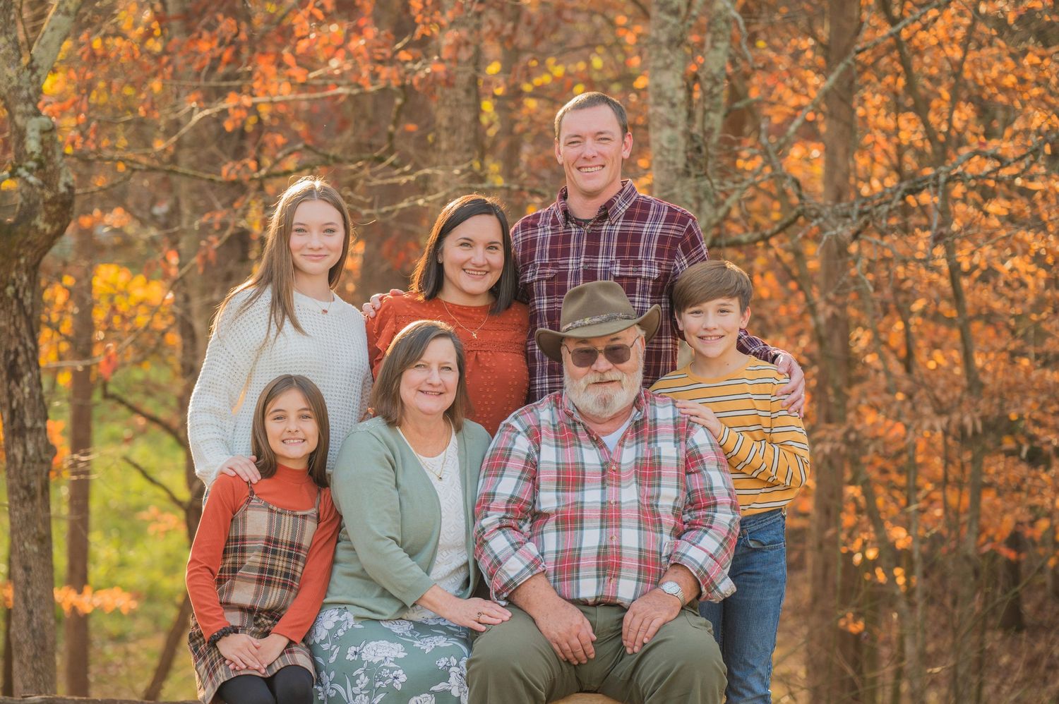 Family portrait outdoors in autumn with vibrant orange and yellow fall foliage in the background at their rental in Sevierville TN.