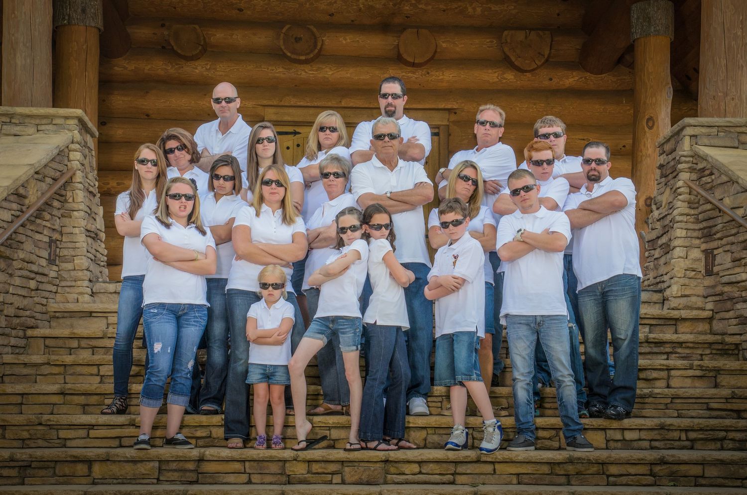 Large family group wearing matching white shirts and blue jeans poses together on the cabin rental in Gatlinburg TN.