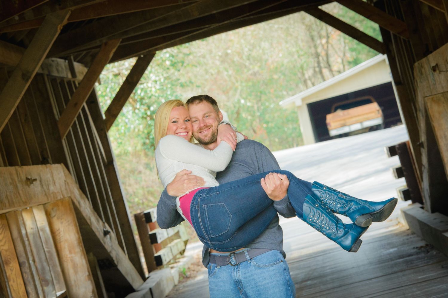 Two people share a playful moment inside a covered wooden rustic bridge structure Pigeon Forge TN.