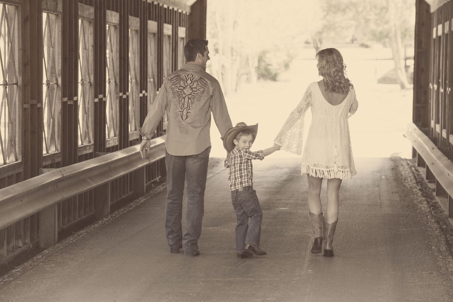 A family walks together hand in hand through a covered bridge in a nostalgic black and white photograph by Gatlinburg photographers tn.