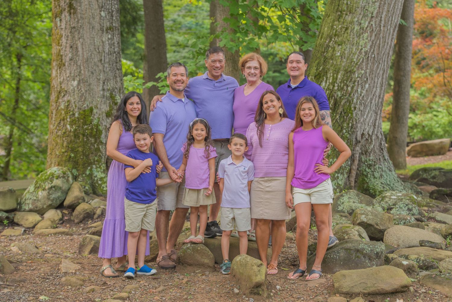 Pigeon Forge Photographers portrait of a family poses for an outdoor family photo among trees wearing coordinated purple and pink outfits.