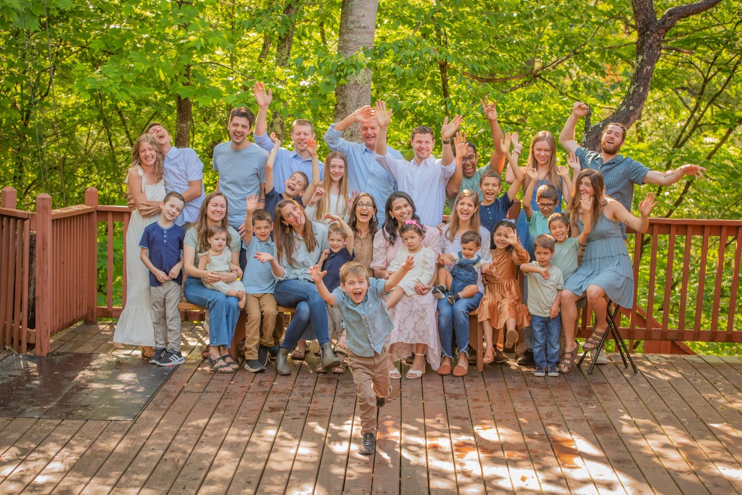 Large family reunion dressed in coordinating light blue and white on a wooden deck by Pigeon Forge Photographers.