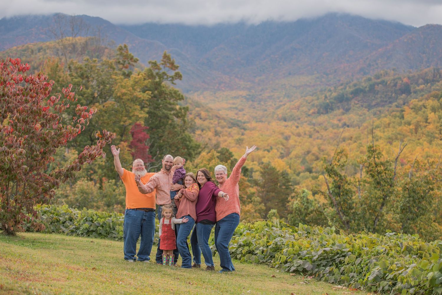 family photographers gatlinburg tn portrait of a family with fall foliage against the Great Smoky Mountains in Tennessee.