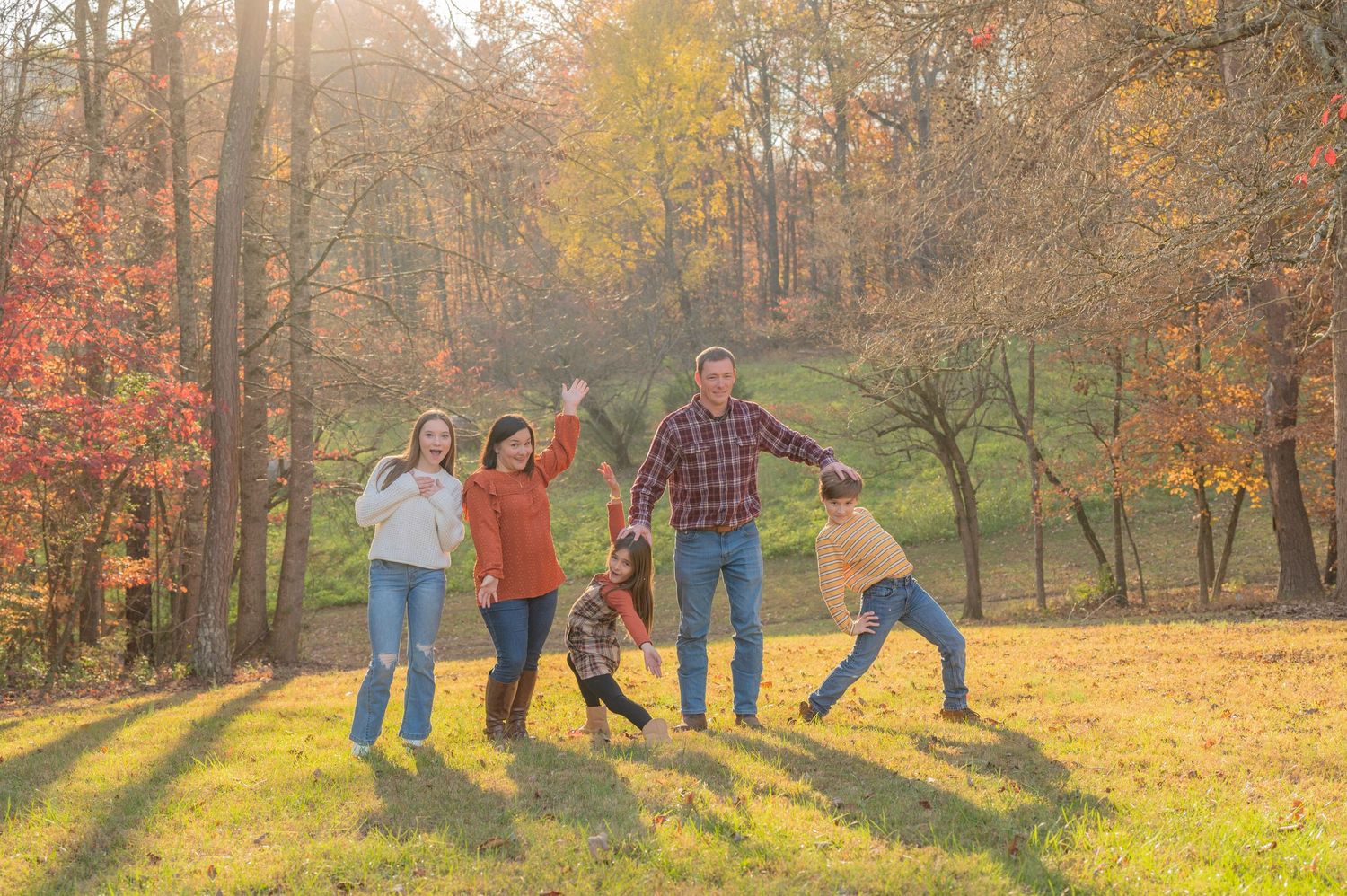 A Gatlinburg Photographer family having fun together in a scenic autumn forest setting with golden sunlight with fall foliage.