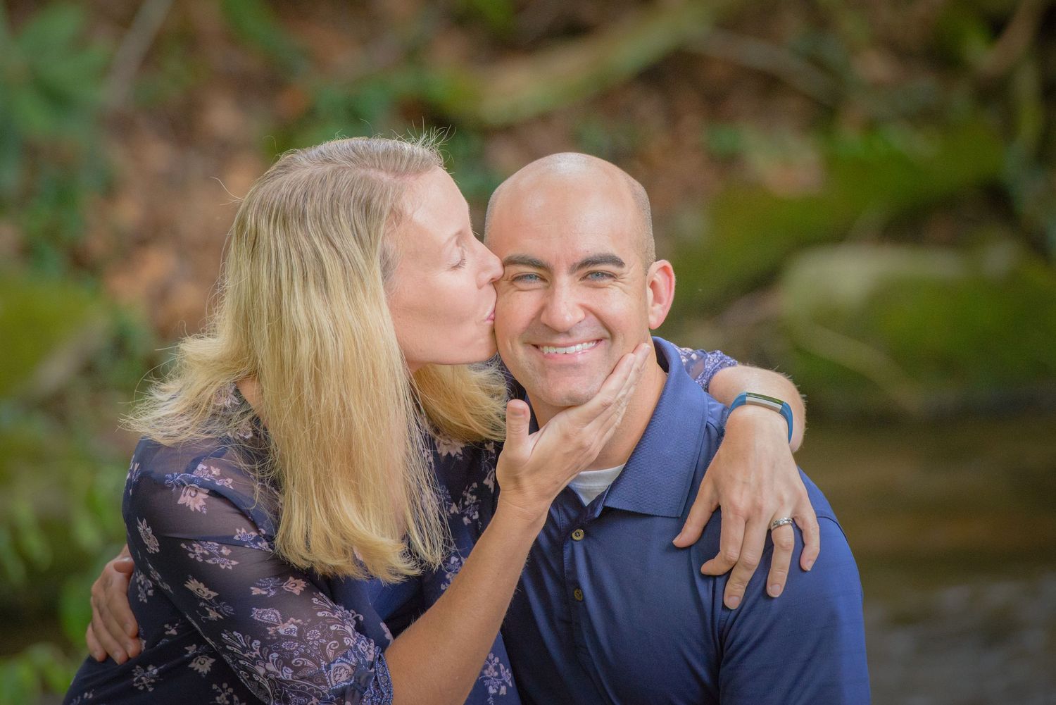 Pigeon Forge Photographer portrait of a loving couple embraces outdoors with natural greenery in the background during a portrait session.