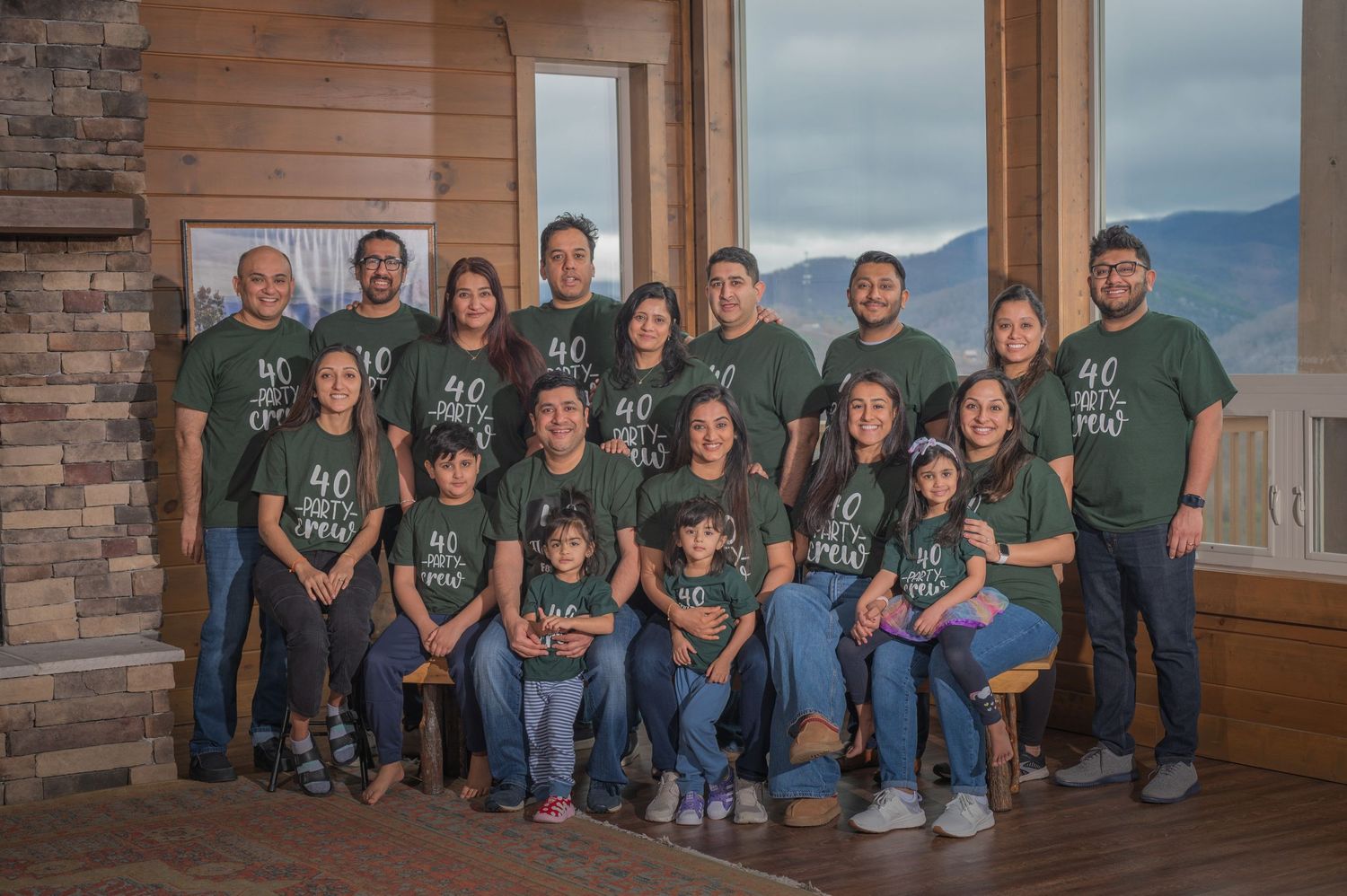 Family reunion wearing matching green t-shirts poses together by large windows with mountain view in background by Pigeon Forge photographer