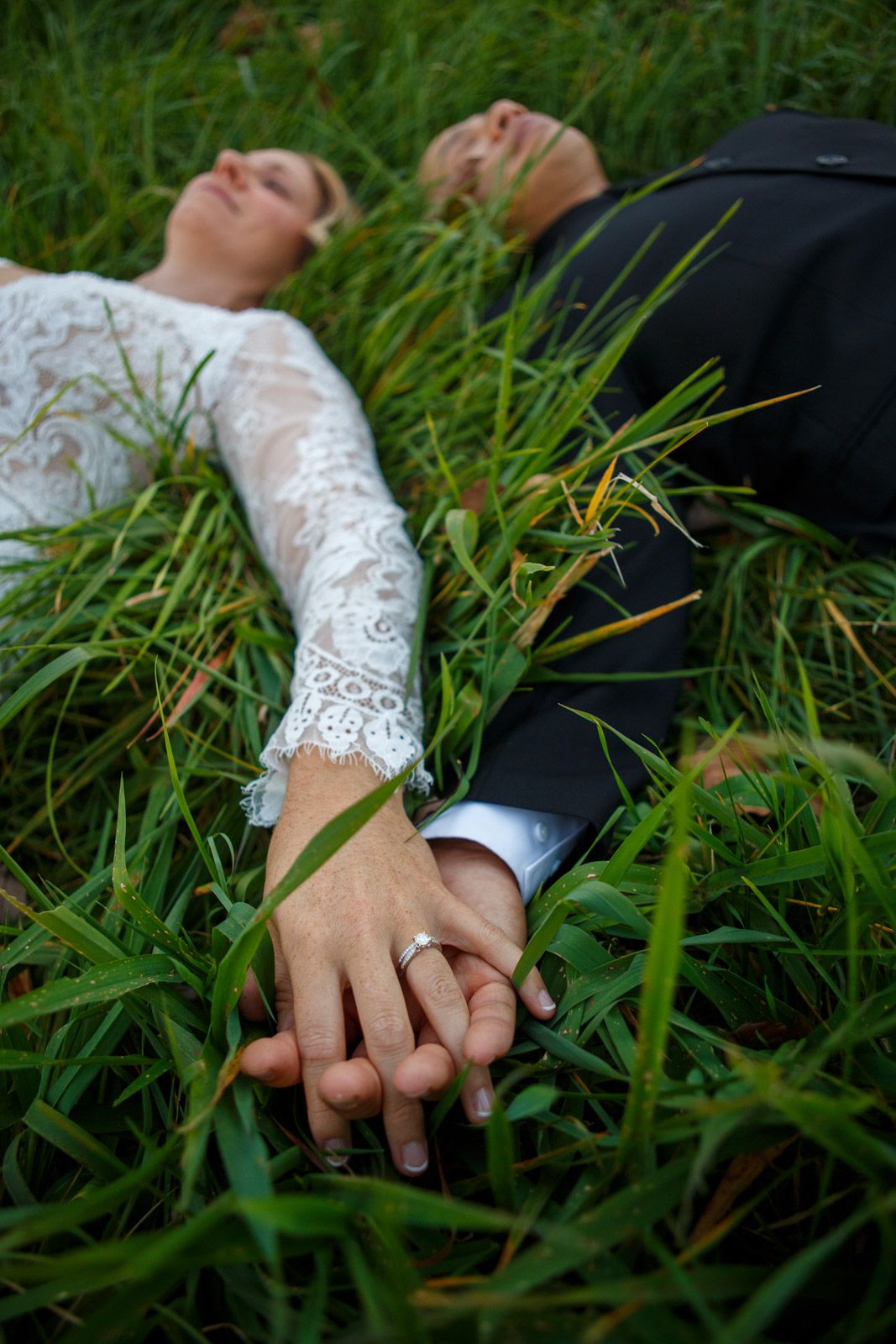 wedding couple laying in the grass ring shot
