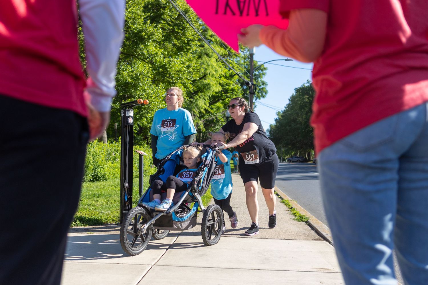 Participants assist others with mobility equipment during an outdoor community walk event.
