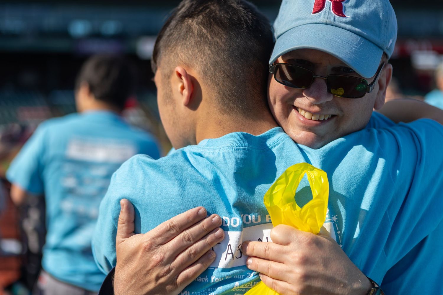 Group of participants in matching light blue shirts gather at an outdoor charity event.