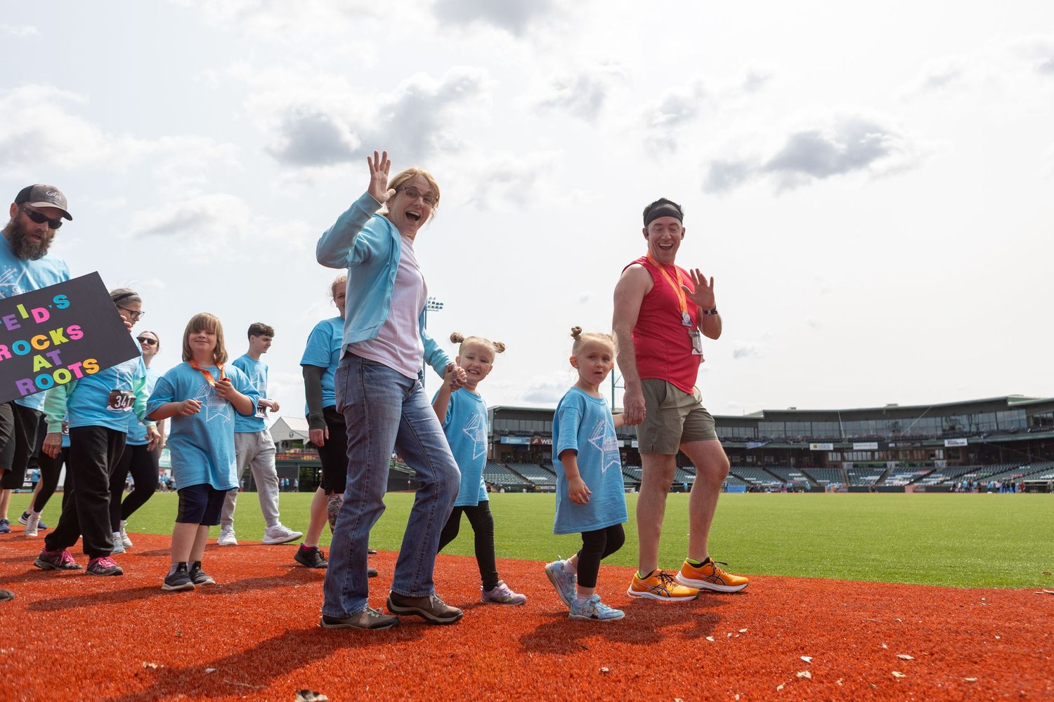 People participating in activities on a baseball field with stadium seating in the background.