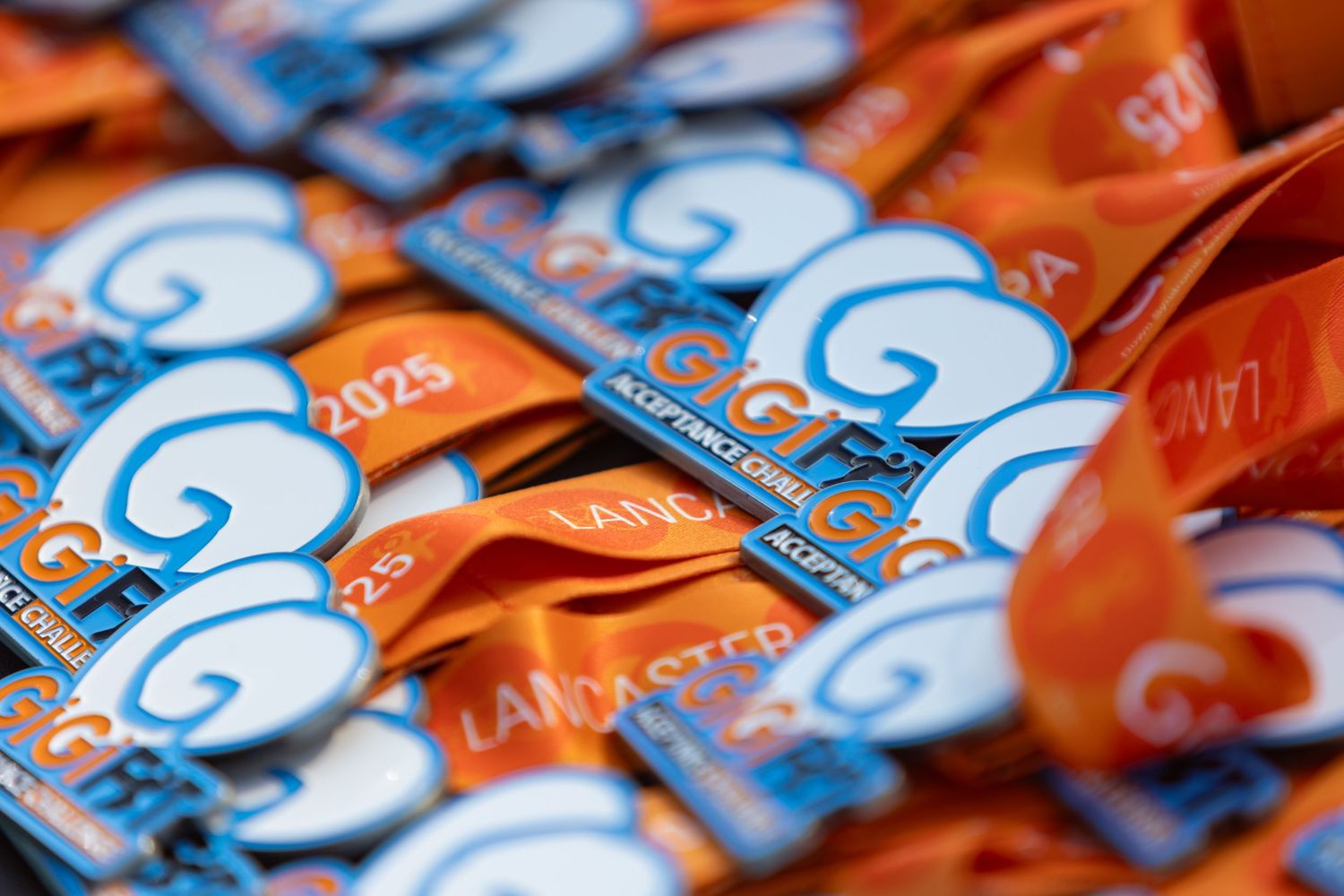 Orange and blue race bibs laid out in rows show event numbers and details.