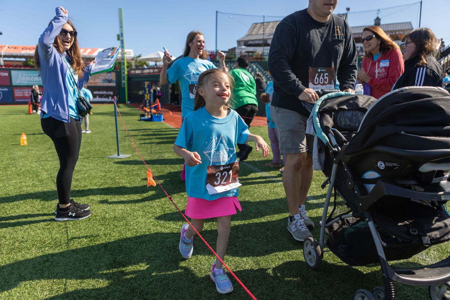 Young participant running on field during outdoor charity event.