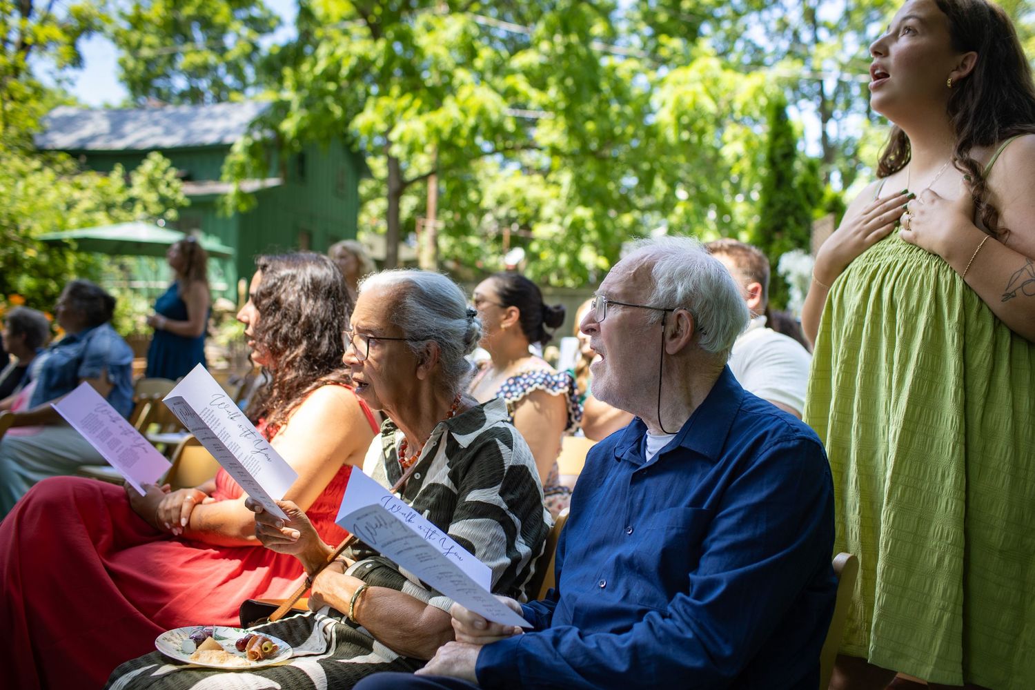 A diverse crowd attentively watches an outdoor event on a sunny summer day.