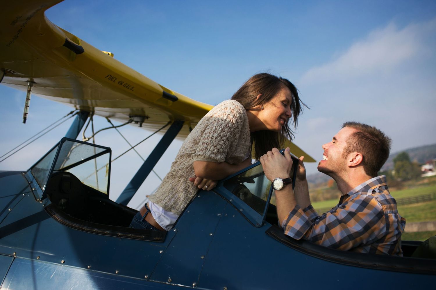 Playful couple sharing romantic moment in vintage aircraft cockpit.