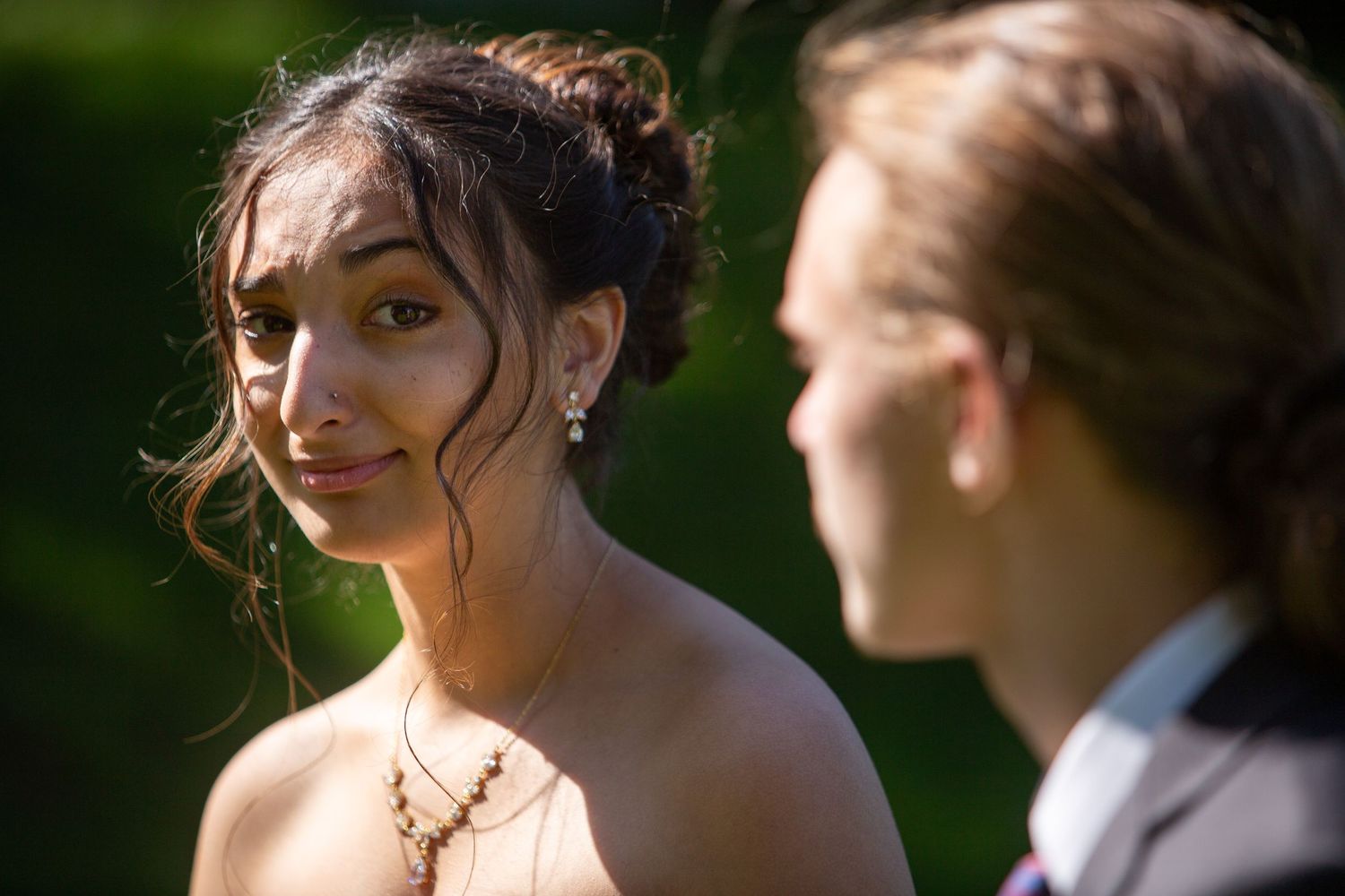 A romantic moment captured during an outdoor wedding as a couple shares a glance in warm sunlight.