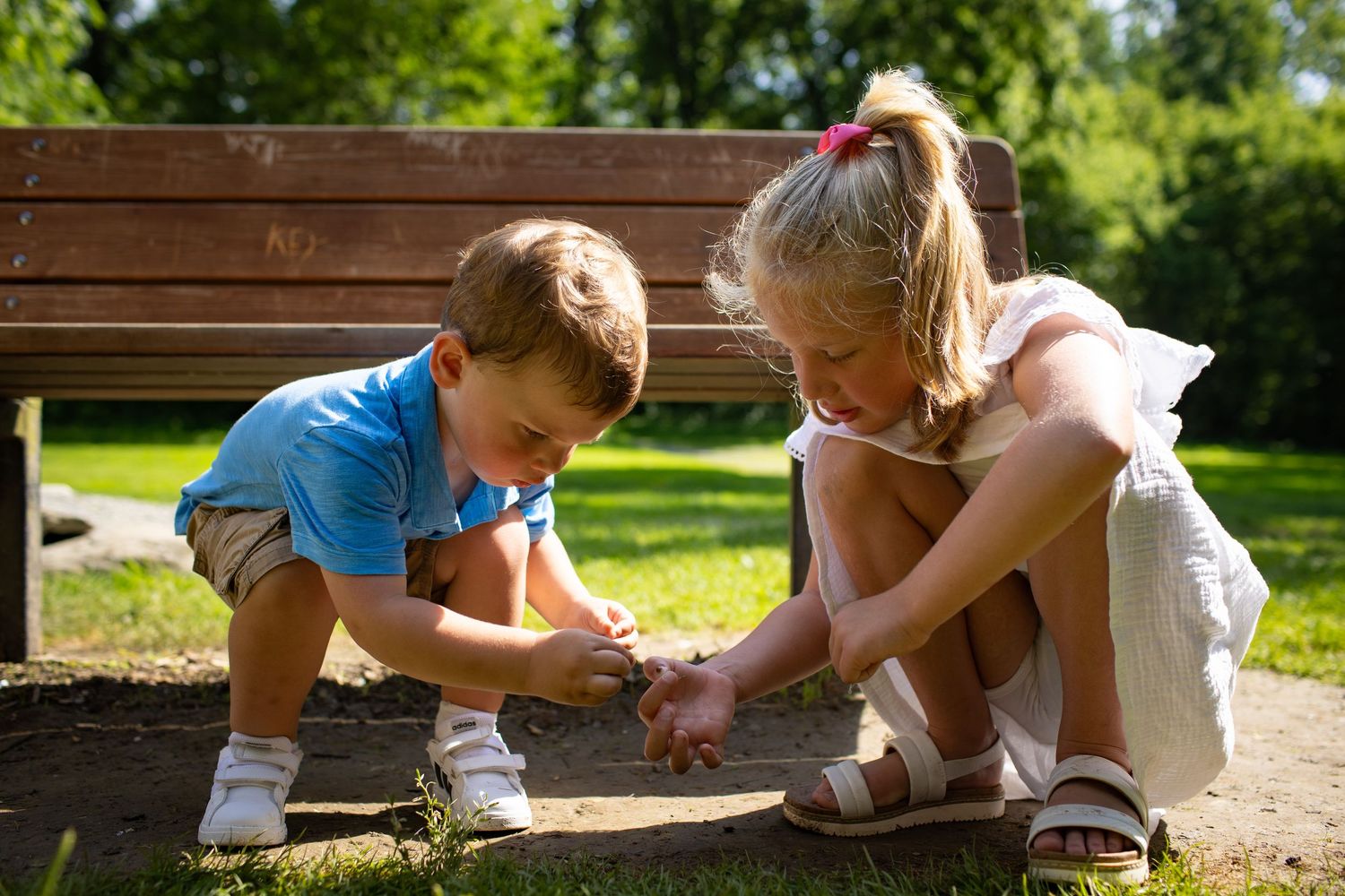 Two people playing together in sand at a park playground on a sunny summer day.