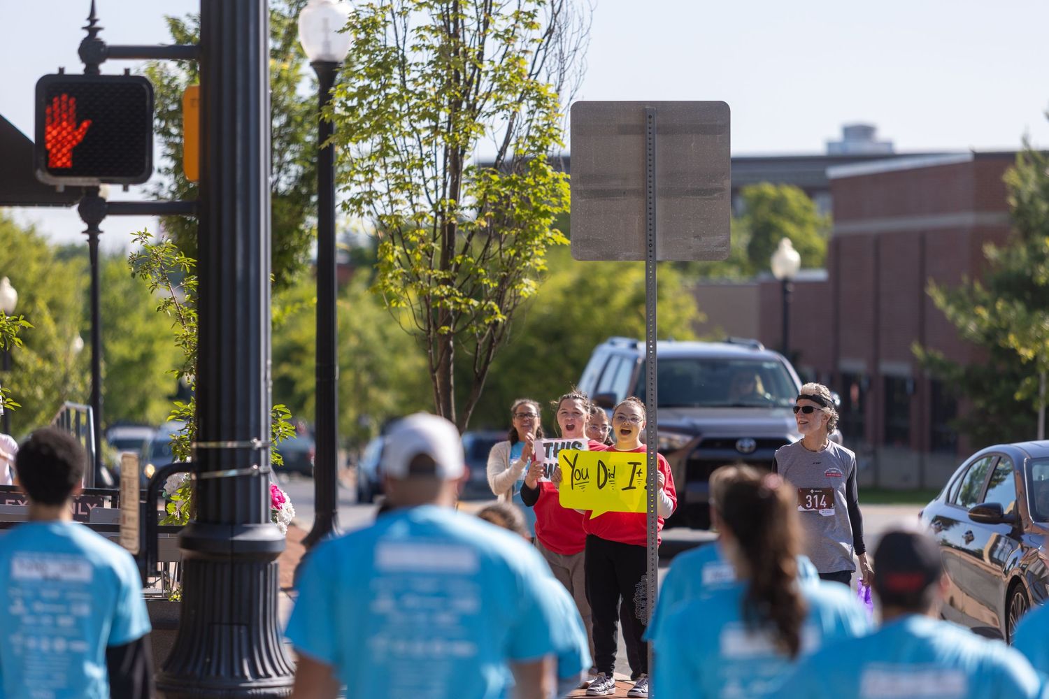 Participants in blue shirts follow safety personnel during an outdoor event.