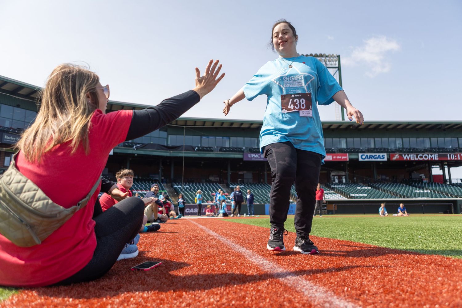 Participants giving high fives while running bases during charity event.