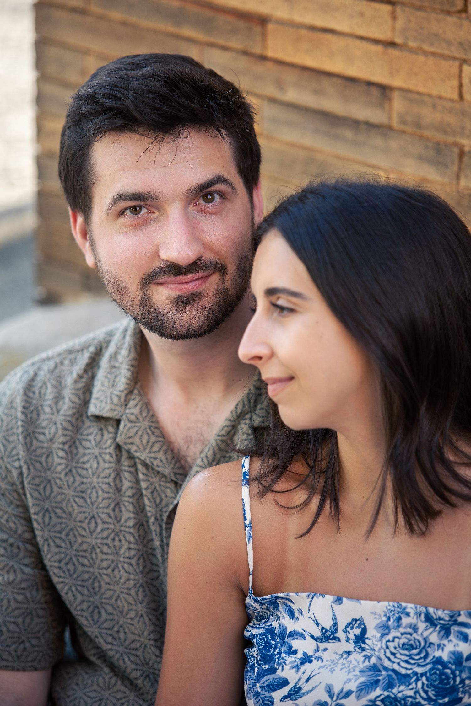 A couple in casual attire share an intimate moment against a wooden wall background.