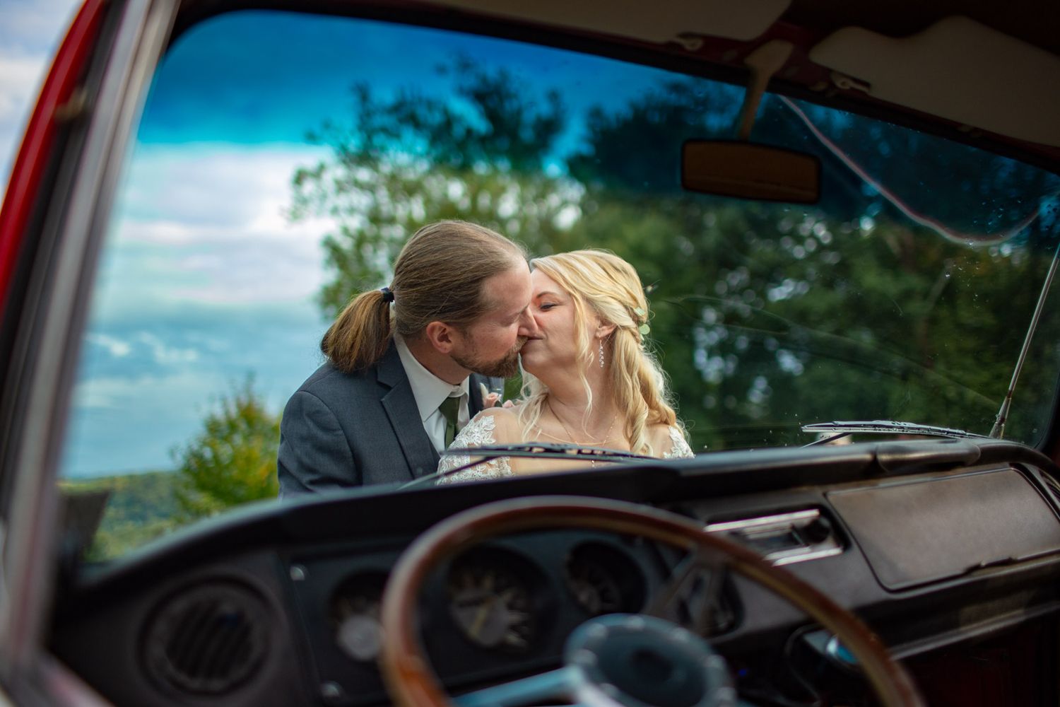 bride and groom kissing through a car window