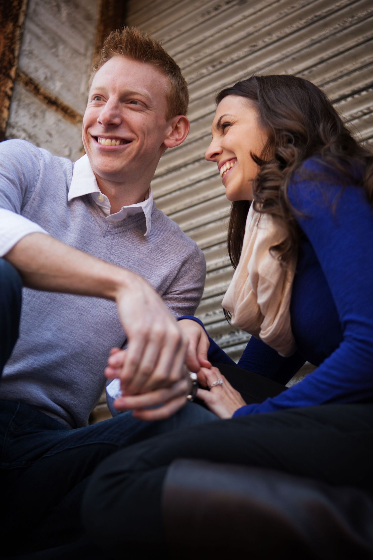 Candid portrait of couple laughing together while sitting outdoors.