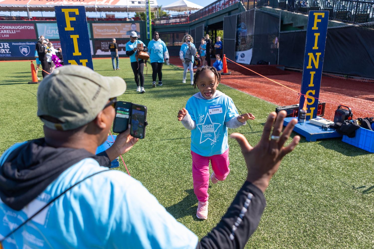 People engaged in activities on baseball field with stadium facilities in background.