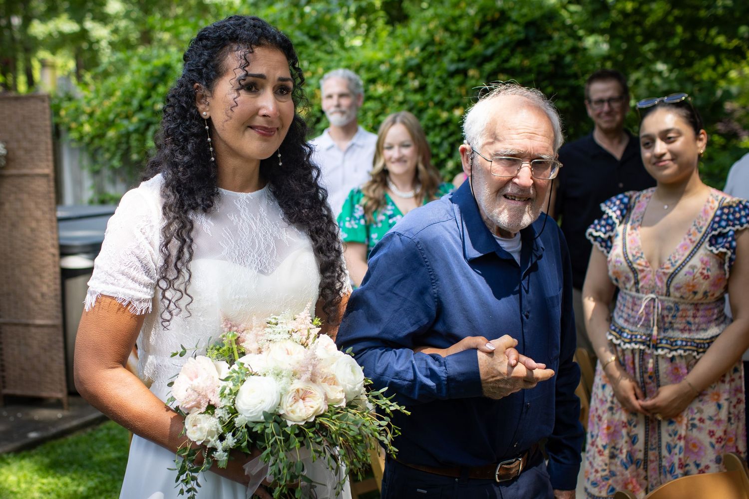Wedding party guests gather outdoors enjoying a casual summer celebration with laughter and conversation.