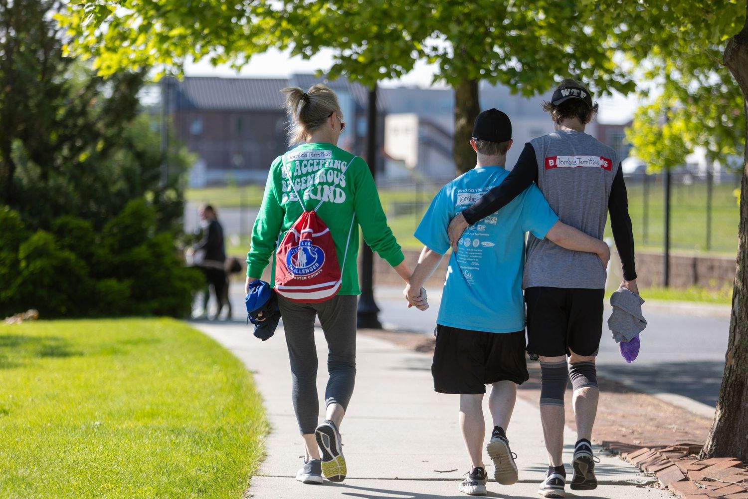 Small group walking together on sunny path during community outdoor event.