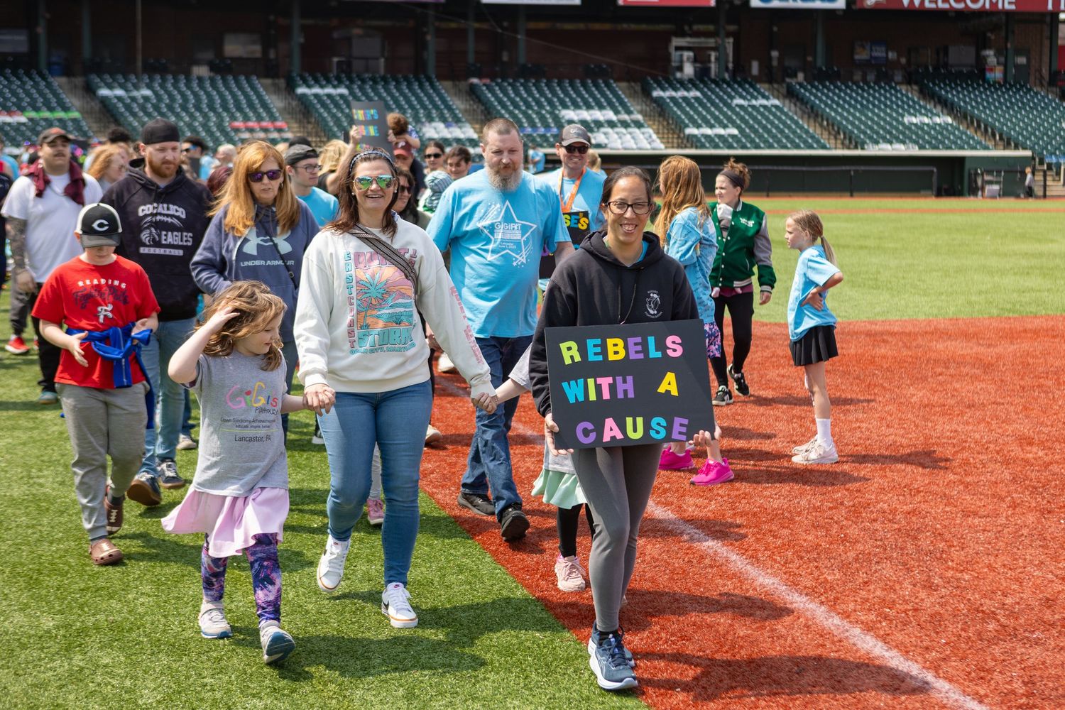 Group walks along baseball field warning track carrying inspirational signs.