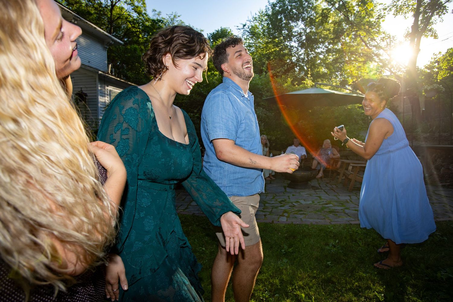 People dancing and celebrating together outdoors at a backyard party during golden hour sunset.
