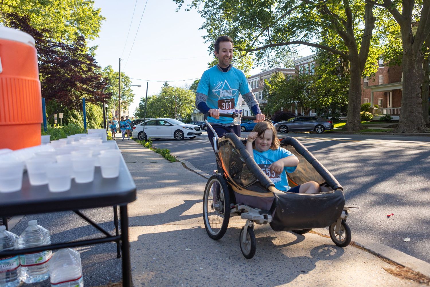 Person pushing stroller during outdoor running event on residential street.
