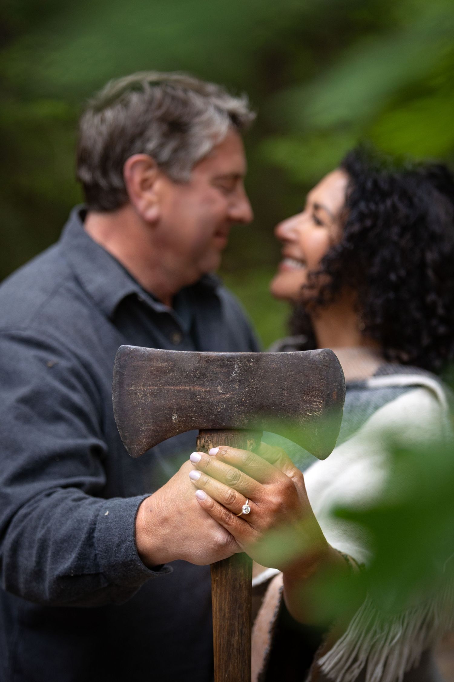 A couple shares an intimate moment outdoors while holding an old wooden axe handle.