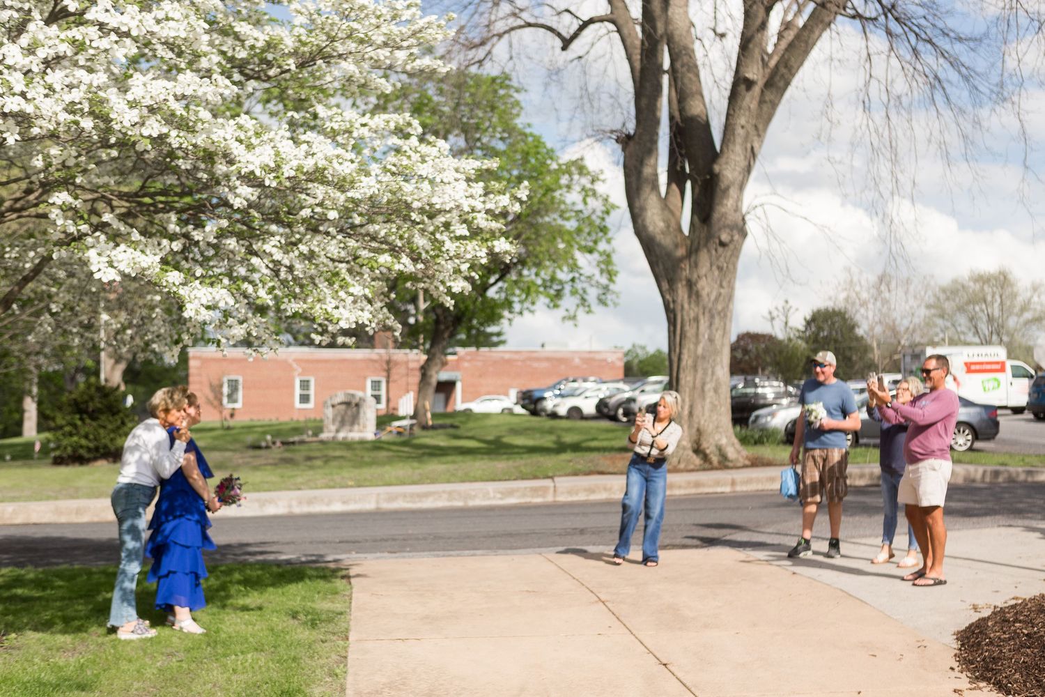 Group gathering outdoors under blooming spring trees.