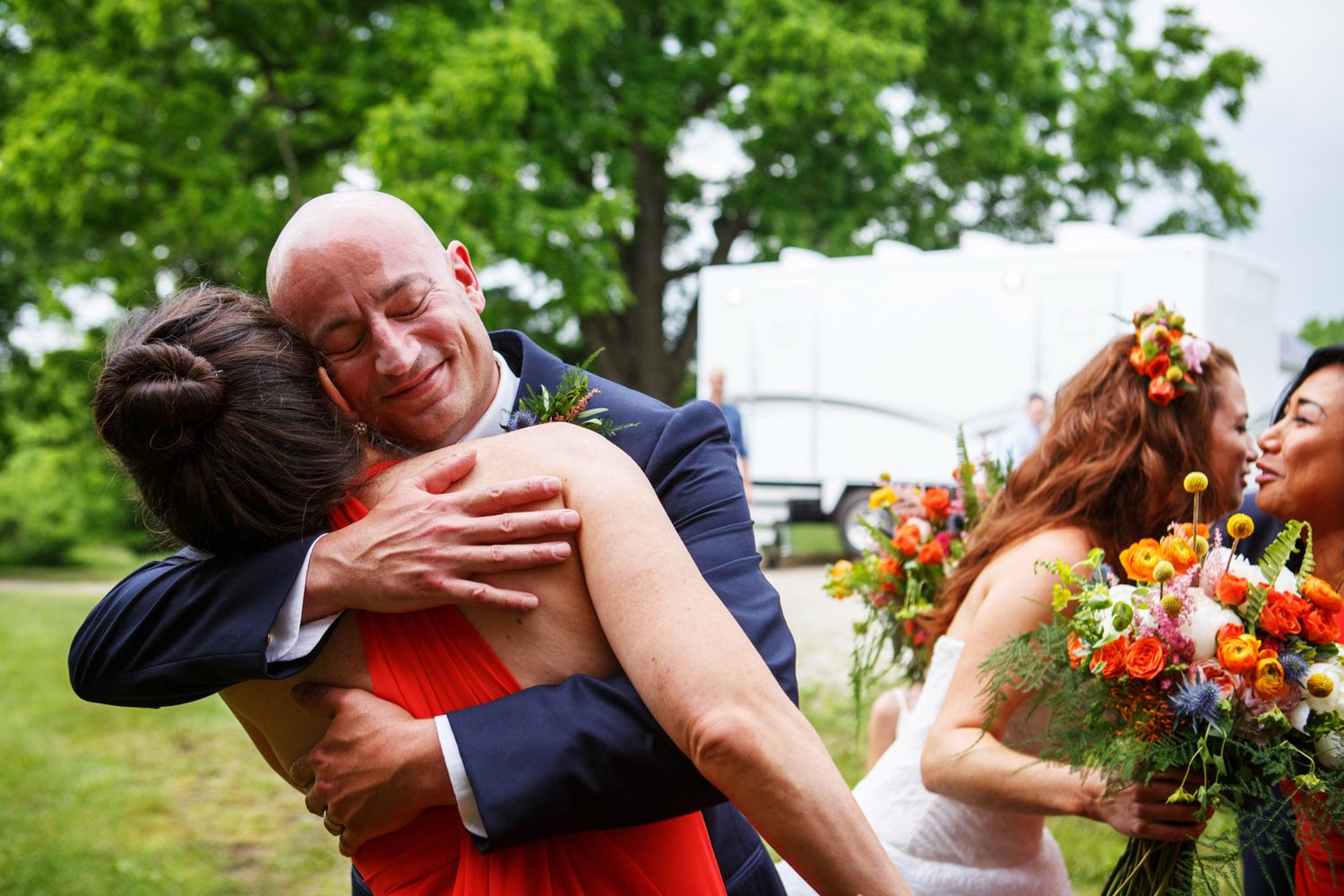 Joyful celebratory moment at an outdoor wedding with bright floral bouquets and emotional embraces in a garden setting.