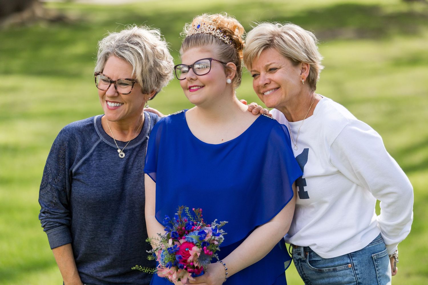 Three people smiling together outdoors with spring flowers.