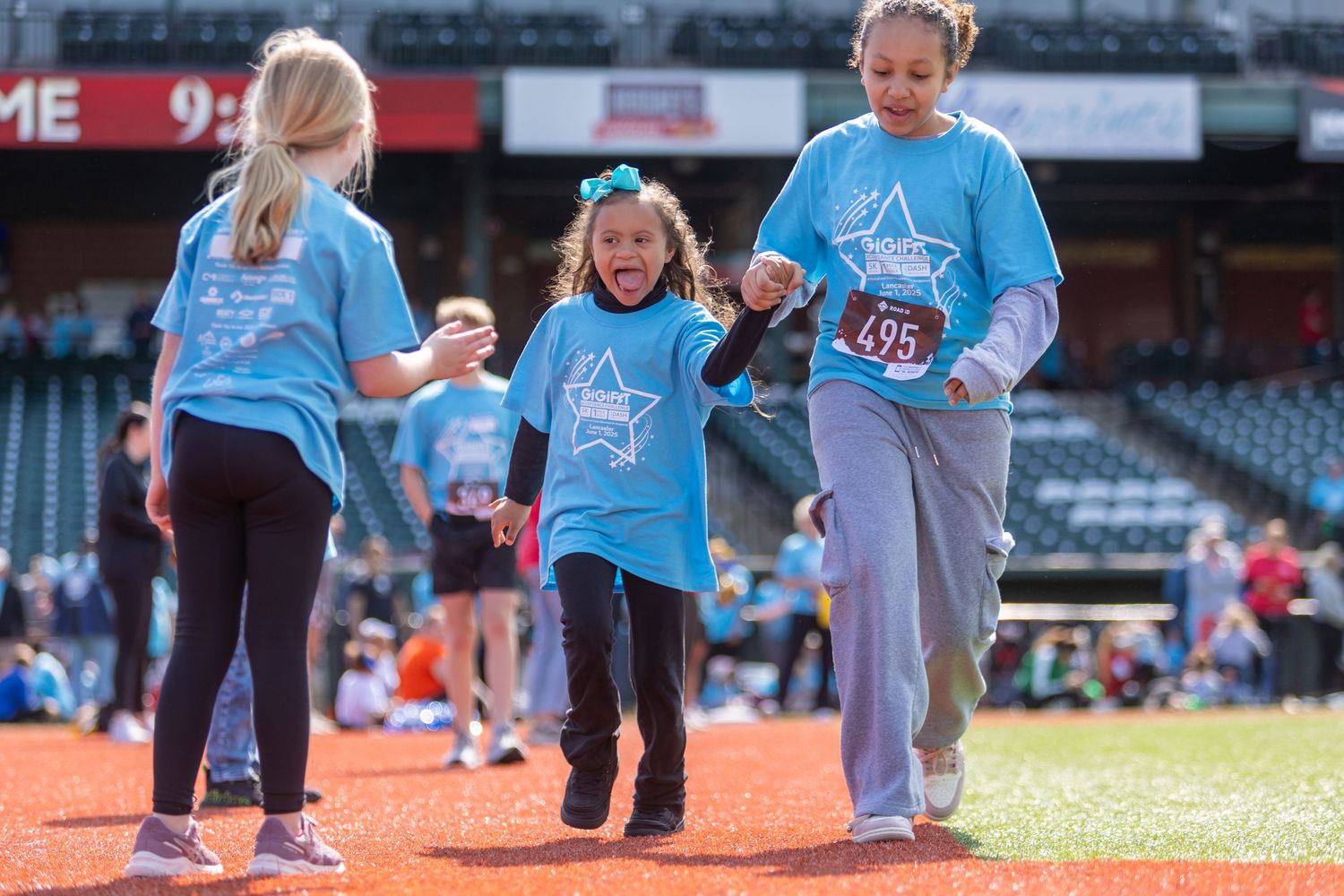 Group in light blue shirts participating in activities on baseball field.