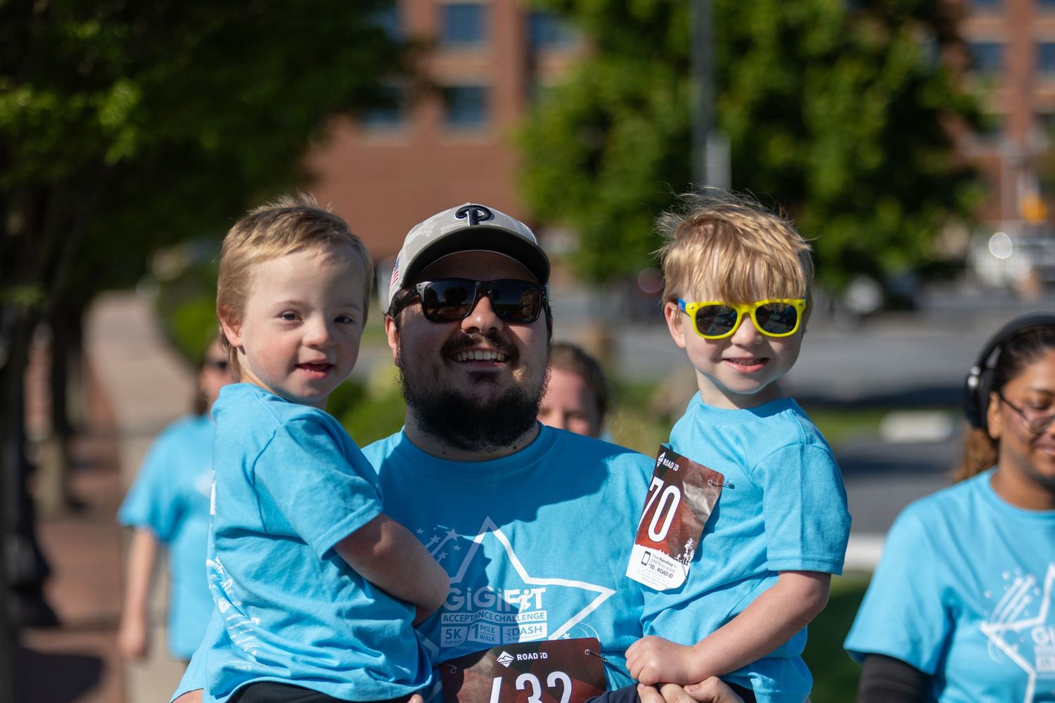 Family group wearing matching blue t-shirts at outdoor community event.