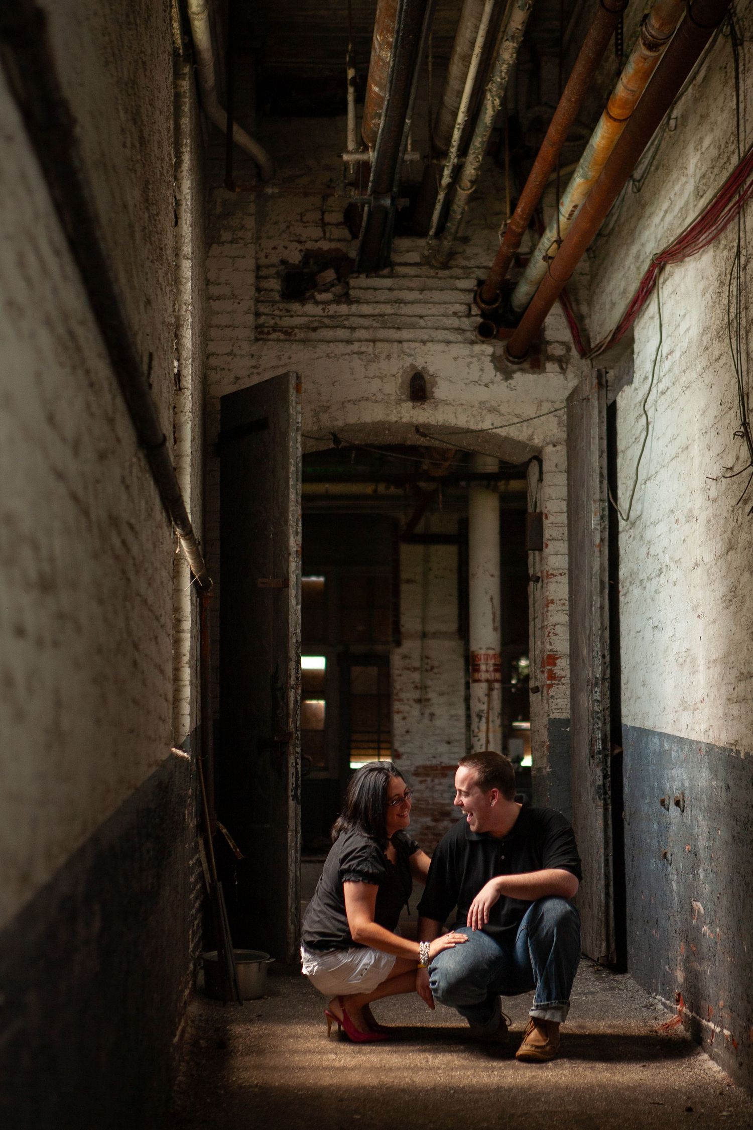 An intimate conversation in a dimly lit industrial hallway with exposed brick walls.