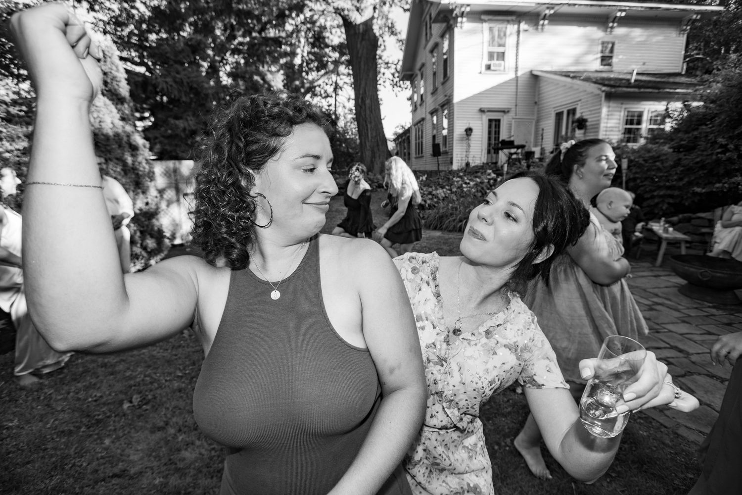 Black and white photo of joyful people dancing together at an outdoor garden party celebration.