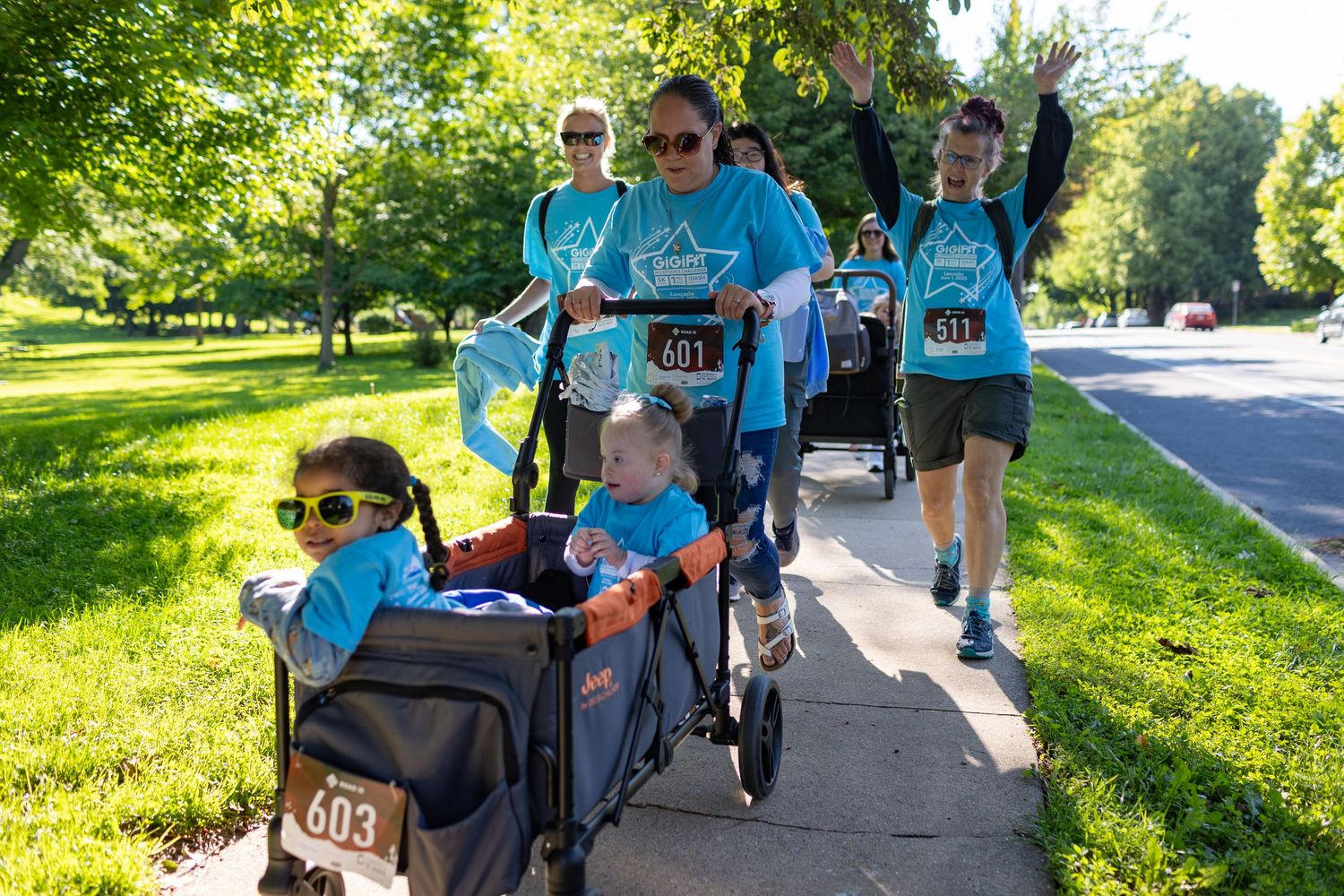 Group of participants walking on sidewalk with stroller during community event.