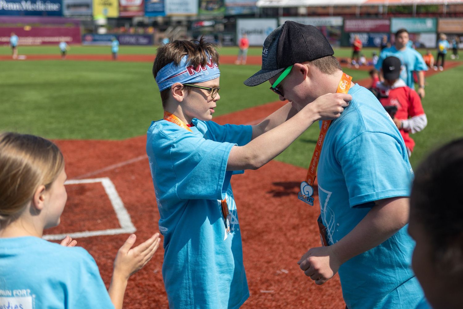 Two people in blue shirts engaged in an activity at a baseball stadium.