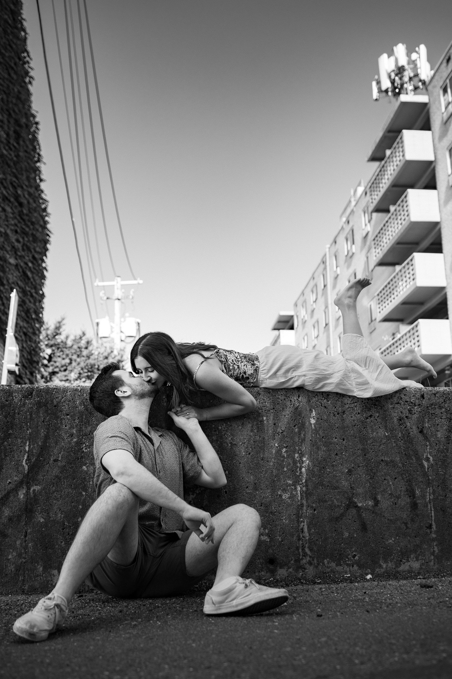 A series of black and white photographs showing a person in dark clothing reclining against a concrete wall outdoors.